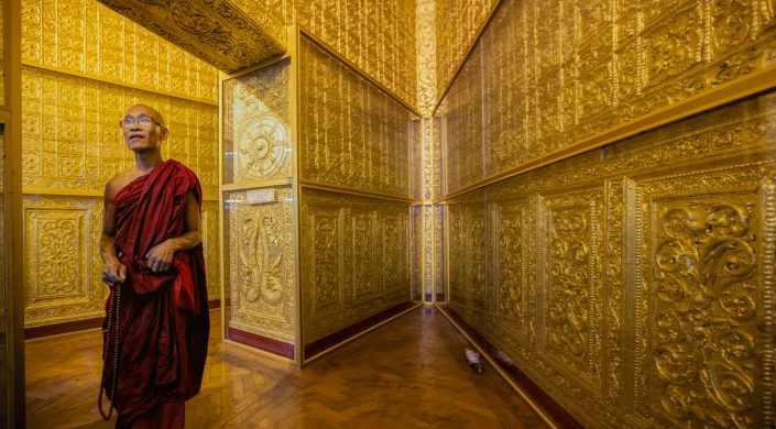 YANGON, MYANMAR – JAN 16: Monk in red robes prays inside Botahtu