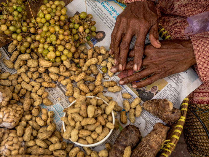 Asian woman selling peanuts on street out of straw basket