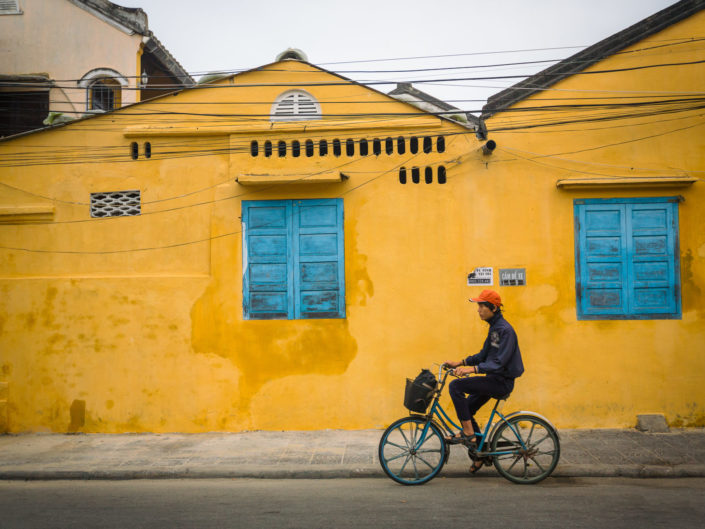 HOI AN, VIETNAM – JAN 8: Locals bicycle past yellow building in