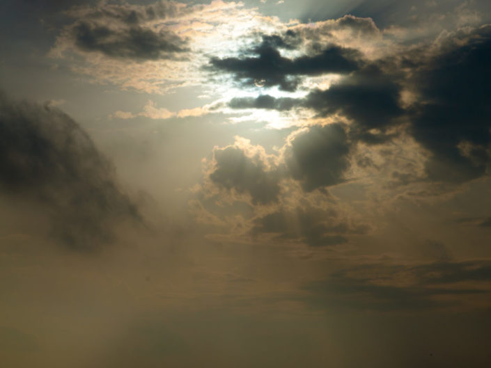 Sun Setting Behind Clouds Over Ocean